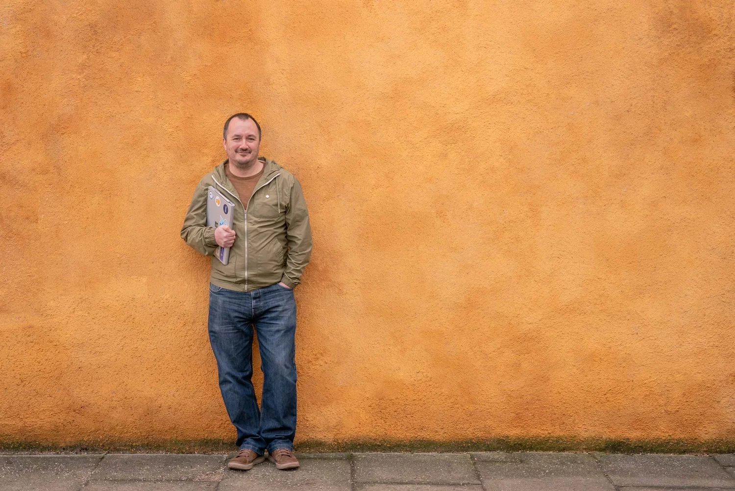 David Hamill leaning against an ochre wall